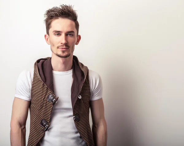 Jeune homme séduisant en gilet marron et pose de t-shirt blanc en studio . — Photo