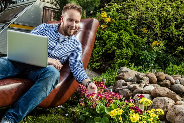 Young handsome man in casual clothes sit in luxury sofa with notebook in summer garden. — Stock Photo, Image