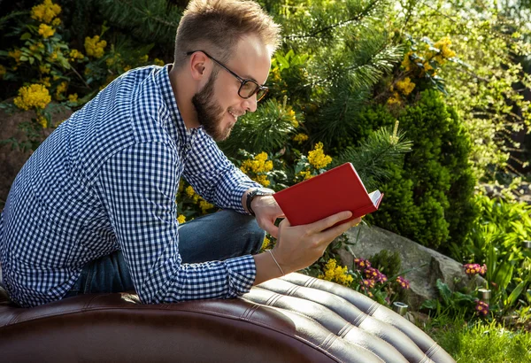 Young handsome man in casual clothes & glasses sit in luxury sofa in summer garden. — 图库照片