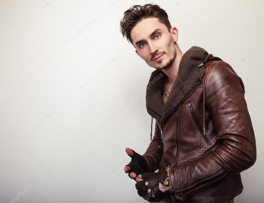 Attractive young man in a brown leather jacket pose in studio.