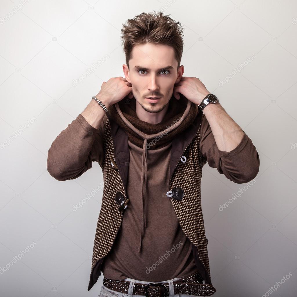 Attractive young man in a brown sweater pose in studio.