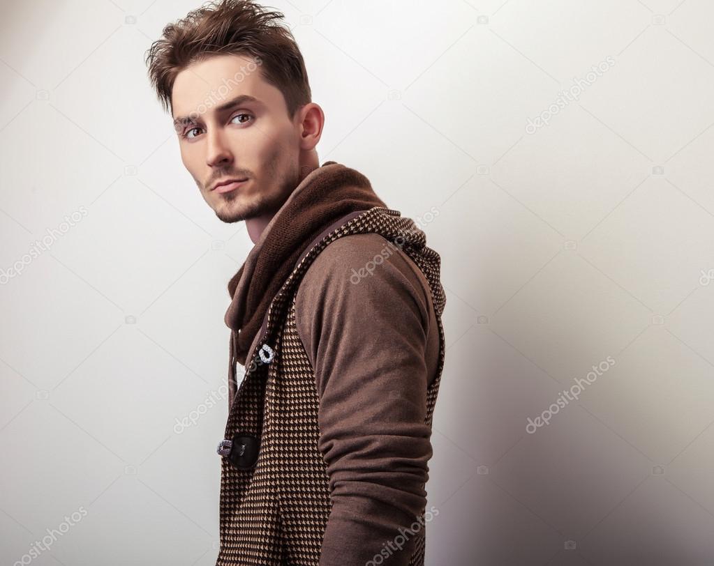 Attractive young man in a brown sweater pose in studio.