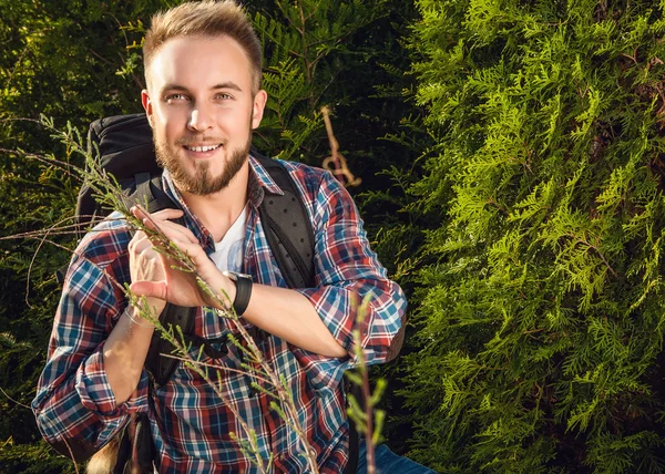 Junger, gutaussehender Mann, Touristenreisender mit Marschrucksack posiert gegen die sommerliche Natur. — Stockfoto