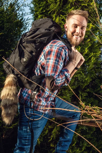 Junger, gutaussehender Mann, Touristenreisender mit Marschrucksack posiert gegen die sommerliche Natur. — Stockfoto