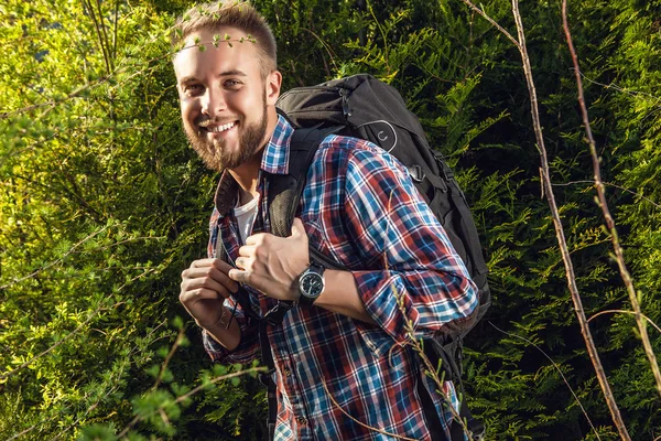 Joven hombre guapo viajero turístico con una mochila de marcha posa contra la naturaleza de verano . —  Fotos de Stock