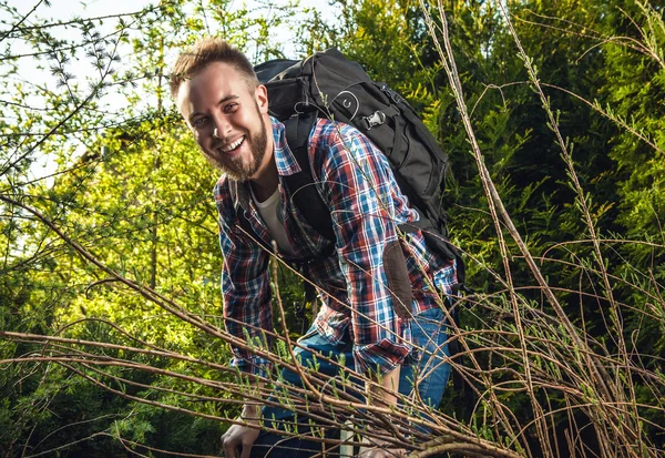 Young handsome man tourist traveler with a marching backpack poses against summer nature. — Stock Photo, Image