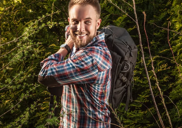 Junger, gutaussehender Mann, Touristenreisender mit Marschrucksack posiert gegen die sommerliche Natur. — Stockfoto