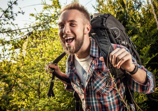 Joven hombre guapo viajero turístico con una mochila de marcha posa contra la naturaleza de verano . —  Fotos de Stock