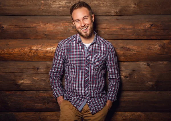 Portrait de jeune bel homme positif contre un vieux mur en bois . — Photo