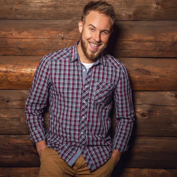 Portrait of young beautiful positive man against old wooden wall. — Stock Fotó