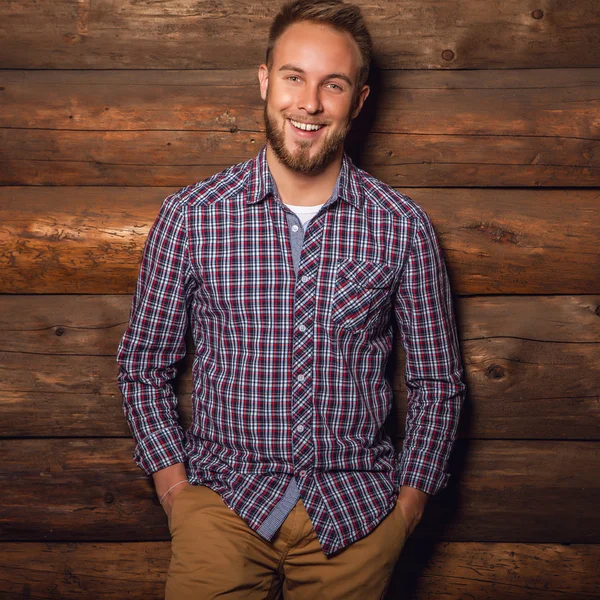 Retrato de un joven hermoso hombre positivo contra una vieja pared de madera . — Foto de Stock