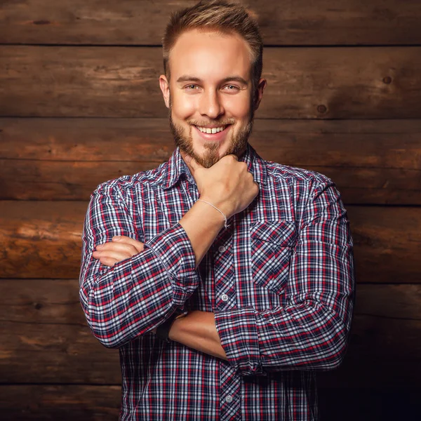 Portrait de jeune bel homme positif contre un vieux mur en bois . — Photo