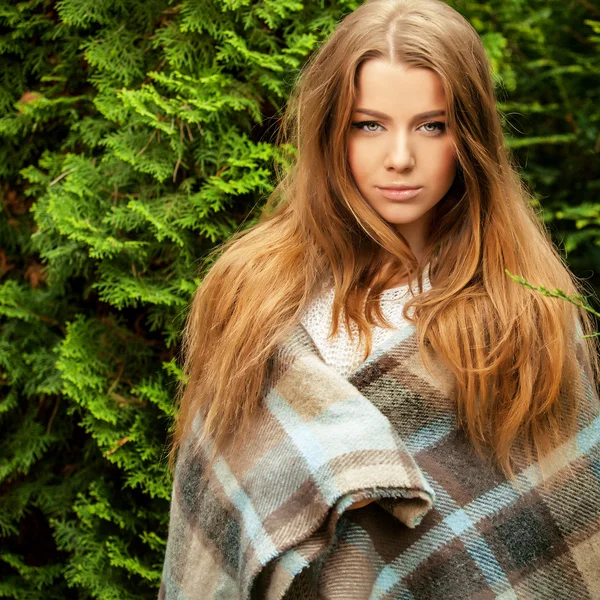 Outdoors portrait of beautiful young girl in casual white sweater & rolled in a plaid. — Stock Photo, Image