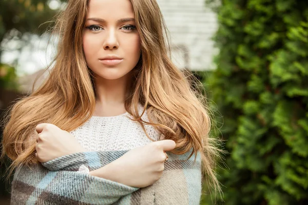 Outdoors portrait of beautiful young girl in casual white sweater & rolled in a plaid. — Stock Photo, Image