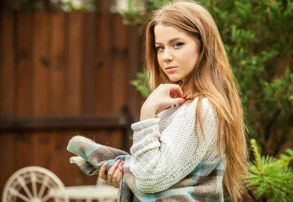 Retrato al aire libre de una hermosa chica joven en suéter blanco casual y enrollado en un cuadros . —  Fotos de Stock