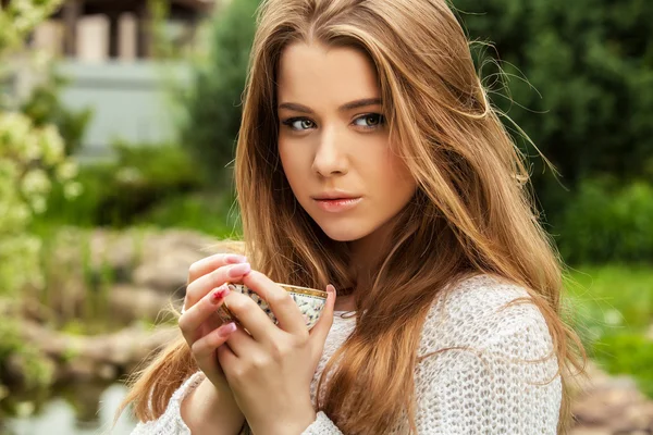 Outdoors portrait of beautiful young girl in casual white sweater with cap of tie. — Stock Photo, Image