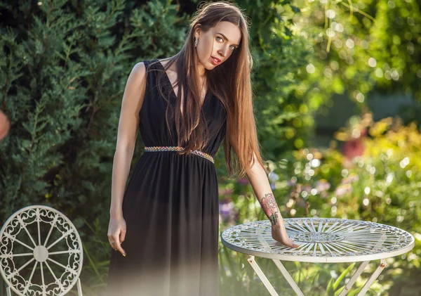 Outdoors portrait of beautiful young woman in luxury black dress posing in summer garden. — Stock Photo, Image