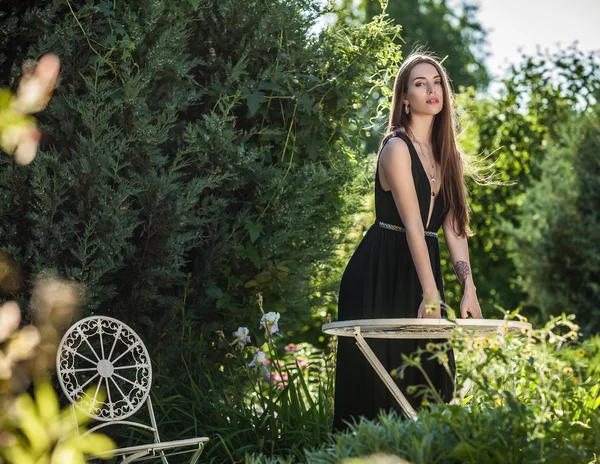 All'aperto ritratto di bella giovane donna in abito nero di lusso in posa nel giardino estivo . — Foto Stock