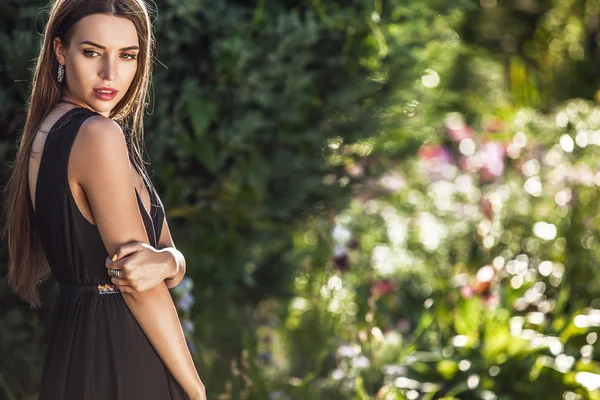 Outdoors portrait of beautiful young woman in luxury black dress posing in summer garden. — 图库照片