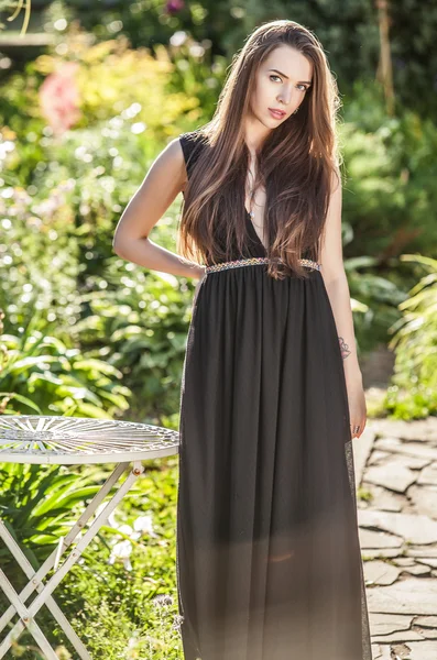 Ao ar livre retrato de bela jovem mulher em luxo vestido preto posando no jardim de verão . — Fotografia de Stock