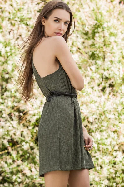 Outdoors portrait of beautiful young woman in fashionable green dress posing in summer garden. — Stock Photo, Image