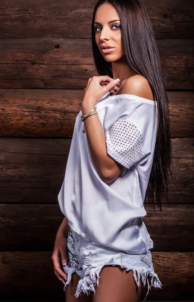 Attractive brunette women in white pose on wooden background. — Stockfoto