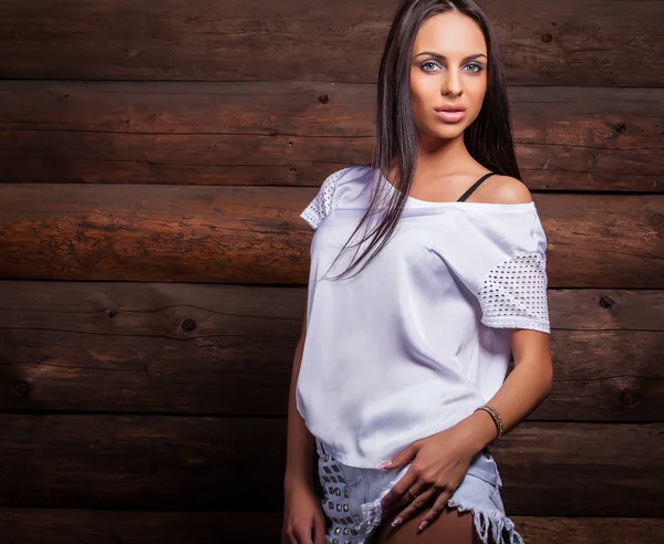 Attractive brunette women in white pose on wooden background. — Zdjęcie stockowe