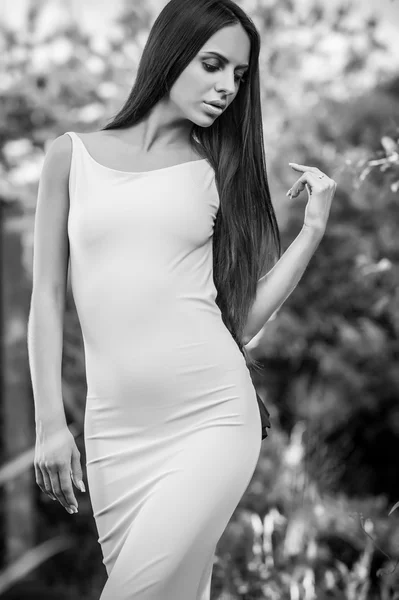 Portrait extérieur de belle jeune fille brune en robe de luxe posant dans le jardin d'été.Photo noir-blanc . — Photo