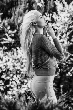 Outdoors portrait of beautiful & positive young blond girl in stylish green sweater. Person against nature.