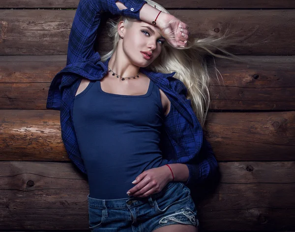 Atractiva joven rubia belleza mujer en azul casual camisa pose sobre fondo de madera . — Foto de Stock