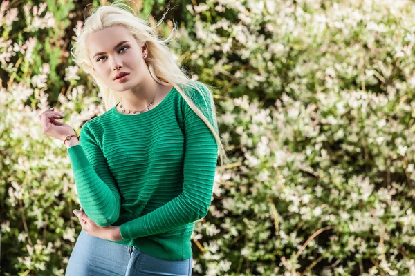Outdoors portrait of beautiful & positive young blond girl in stylish green sweater. Person against nature. — Stockfoto