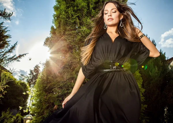 Outdoors portrait of beautiful young girl in luxury long black dress posing in summer garden. — Stock Photo, Image