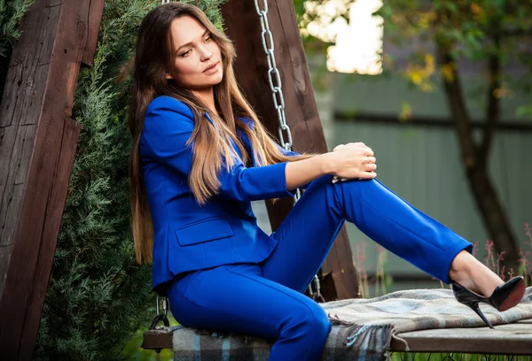 Attractive young woman in official blue suit poses in summer garden. — Stock Fotó