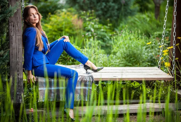 Привлекательная молодая женщина в официальных синих костюмах позирует в летнем саду . — стоковое фото