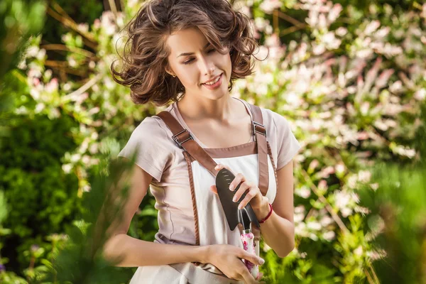 Outdoors portrait of positive young woman in overalls which posing in solar summer garden. — Stock Photo, Image