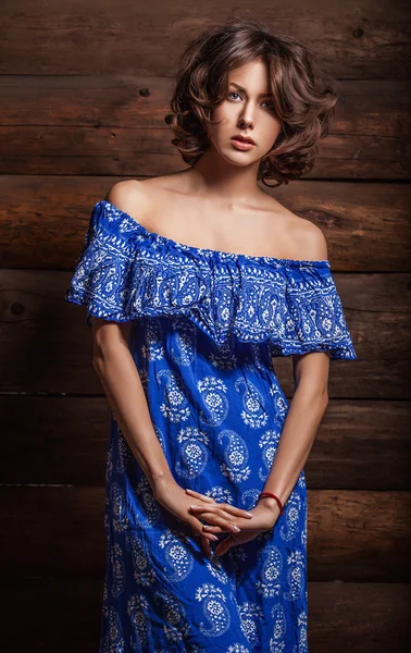 Atraente jovem morena beleza mulher em azul vestido casual pose contra fundo de madeira . — Fotografia de Stock