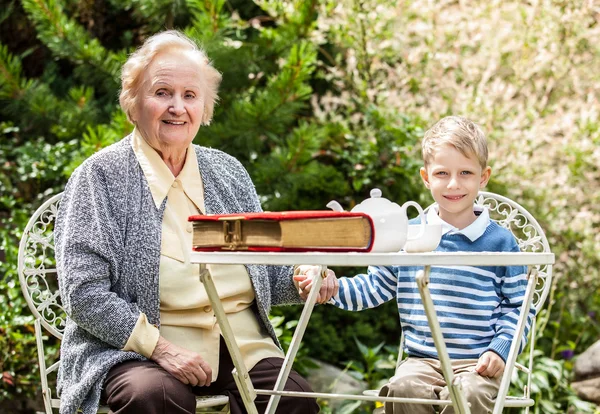 Positive grandmother and grandson spent time together in summer solar garden. — ストック写真