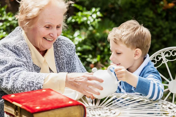 Positive grandmother and grandson spent time together in summer solar garden. — ストック写真