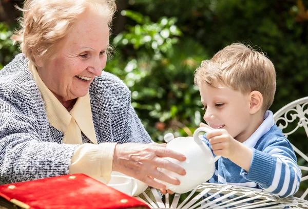 Positive grandmother and grandson spent time together in summer solar garden. — Stock Photo, Image