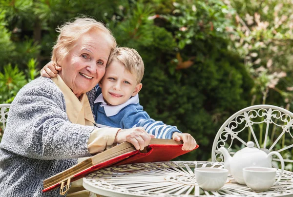 Positive grandmother and grandson spent time together in summer solar garden. — Stock Photo, Image