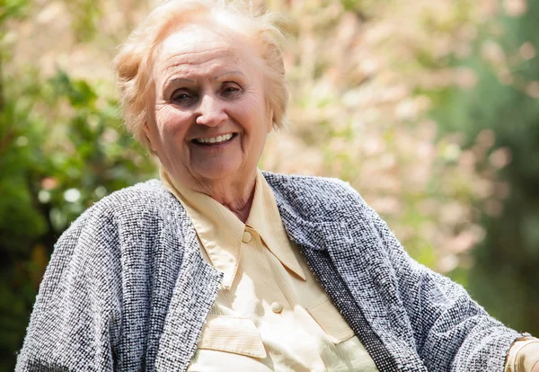 Retrato de la vieja abuela sonriente. Foto sobre fondo de la naturaleza . —  Fotos de Stock