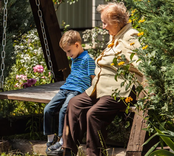 Positive grandmother and grandson spent time together in summer solar garden. — Stockfoto