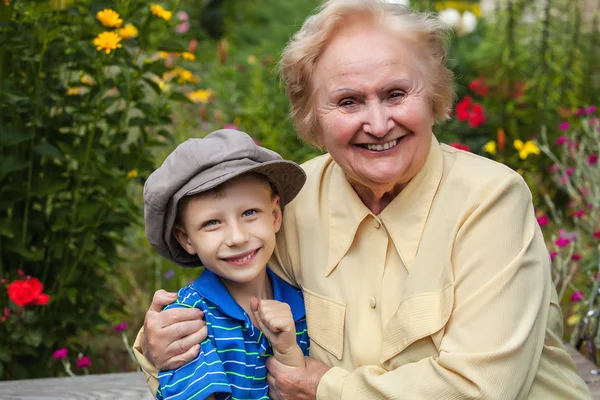 Positive grandmother and grandson spent time together in summer solar garden. — ストック写真