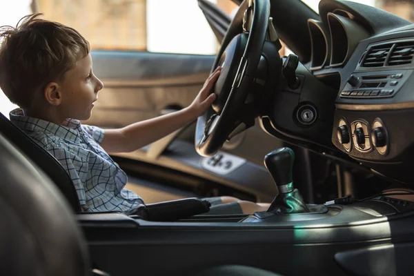 Ritratto all'aperto di bambino biondo felice che esplora salone di auto sportive . — Foto Stock