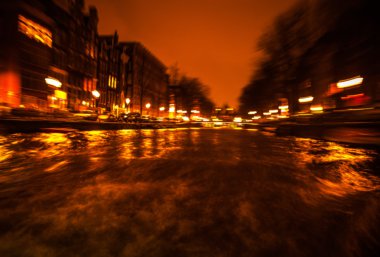 Gece aydınlatma yansımaları hareket eden Amsterdam kanallarında tekne gezisi. Arka plan olarak bulanık soyut fotoğraf.