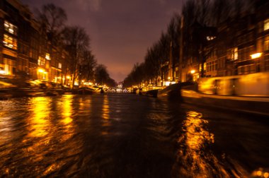 Gece aydınlatma yansımaları hareket eden Amsterdam kanallarında tekne gezisi. Arka plan olarak bulanık soyut fotoğraf.