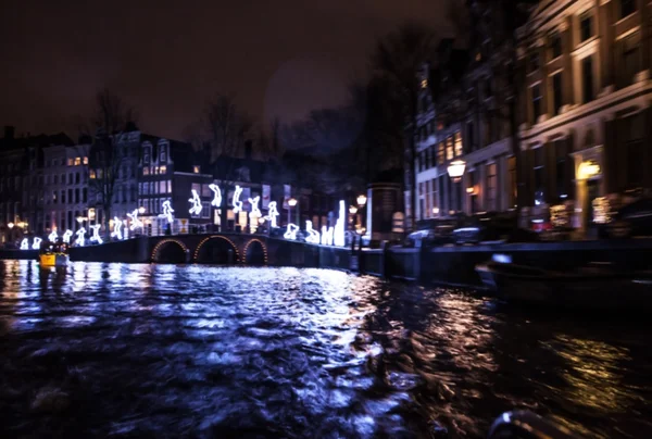 Riflessioni di illuminazione notturna nei canali di Amsterdam da barca da crociera in movimento. Foto astratta offuscata come sfondo . — Foto Stock