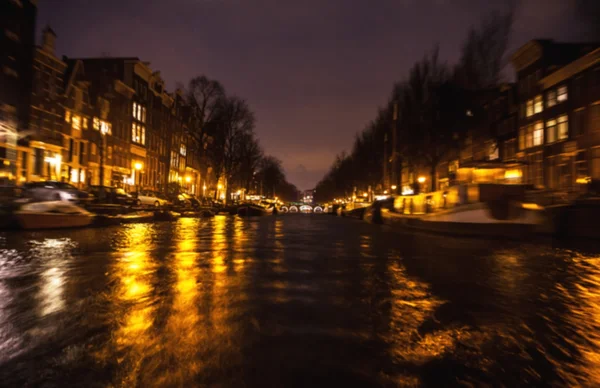Riflessioni di illuminazione notturna nei canali di Amsterdam da barca da crociera in movimento. Foto astratta offuscata come sfondo . — Foto Stock