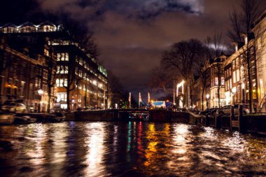 Gece aydınlatma yansımaları hareket eden Amsterdam kanallarında tekne gezisi. Arka plan olarak bulanık soyut fotoğraf.