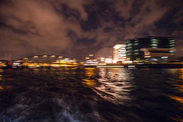 Natt belysning reflektioner i Amsterdams kanaler från att flytta kryssning båt. Suddig abstrakt foto som bakgrund. — Stockfoto